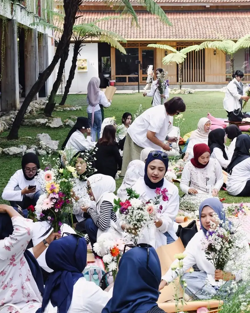Kelas merangkai bunga di halaman rumput dengan puluhan peserta