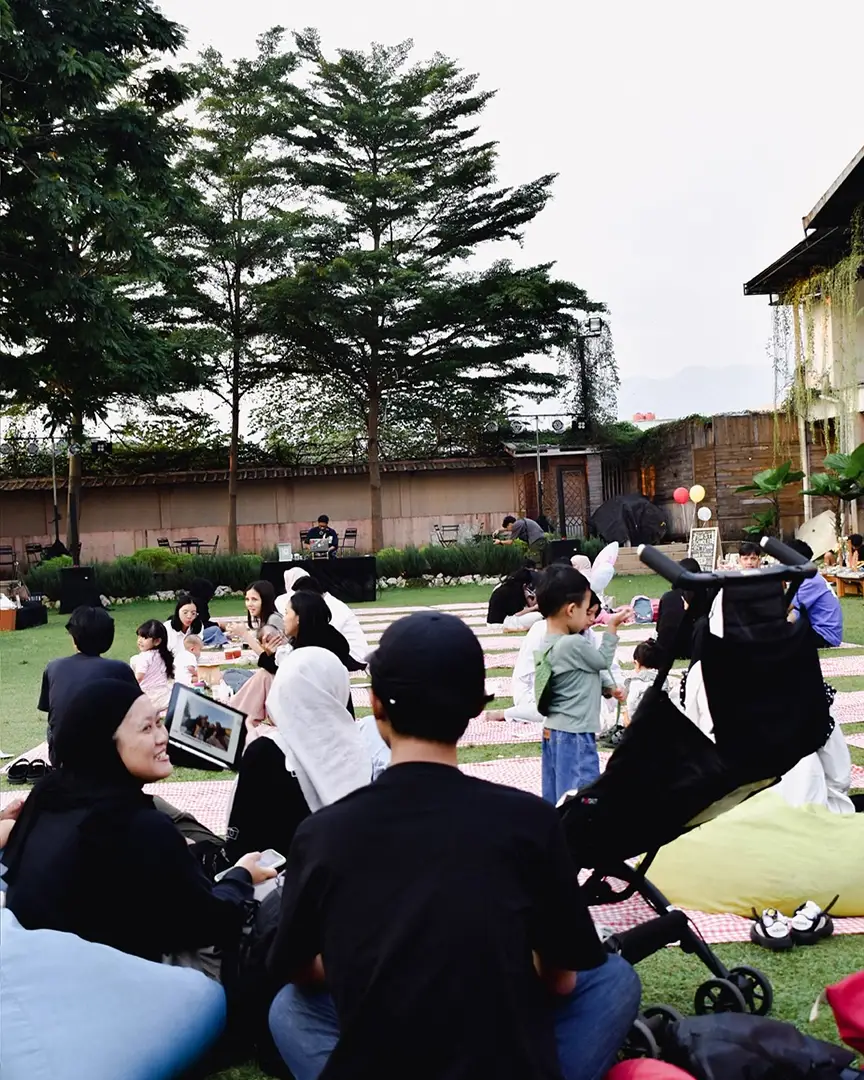Keluarga piknik di rumput dengan anak-anak bermain di dekatnya