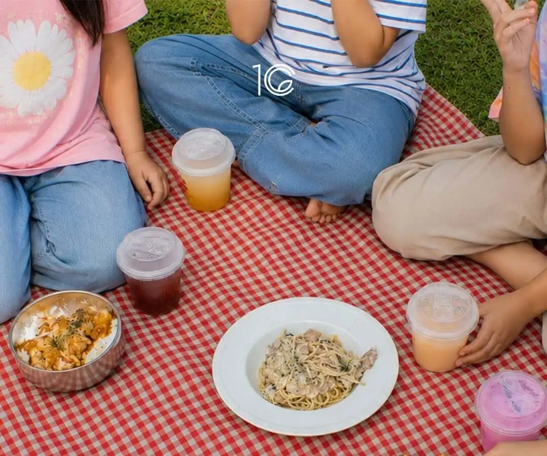 Makanan dan minuman dingin digelar di atas tikar piknik kotak-kotak